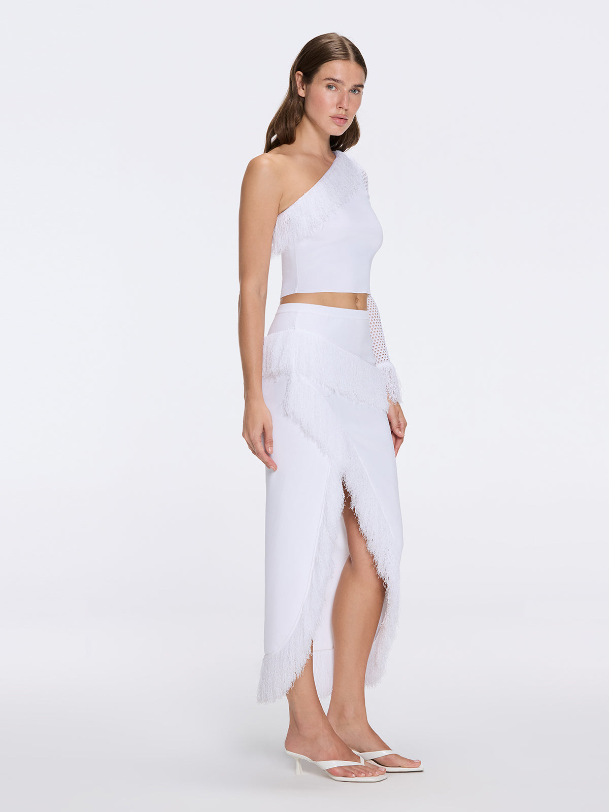 Monroe White One-Shoulder Knit Top with Fringe & Mesh Sleeve | Moeva | Crop Top | Each week unveils new pieces—luxury swimwear, fluid resort silhouettes, and elevated summer-to-evening essentials designed to carry you from coastal escapes to city nights.